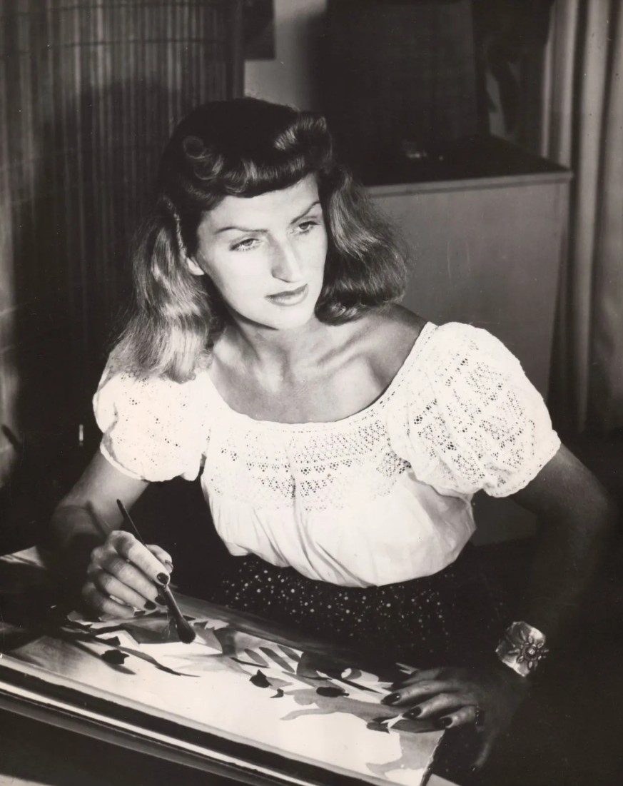 Portrait of animator and Disney artist Mary Blair at work, surrounded by vibrant, colorful concept sketches.