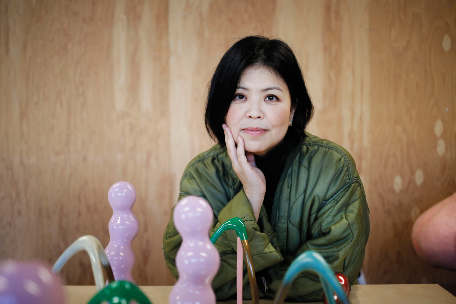 Artist Masako Miki standing among her colorful, semi-abstract, and playful large-scale felted sculptures.