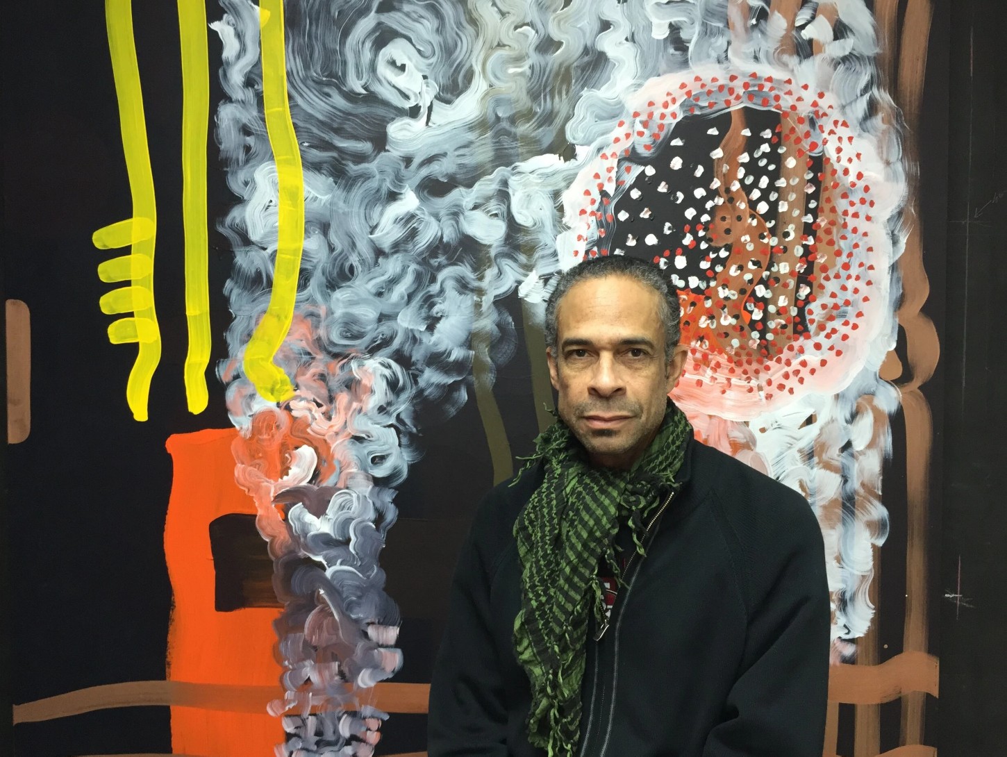 Artist Peter Wayne Lewis posing in front of a large, vibrant abstract painting filled with lyrical brushstrokes.