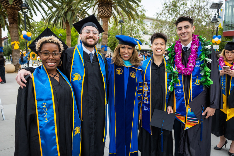 President Cynthia Teniente-Matson poses for a photo with a group of San José State University graduates on commencement day