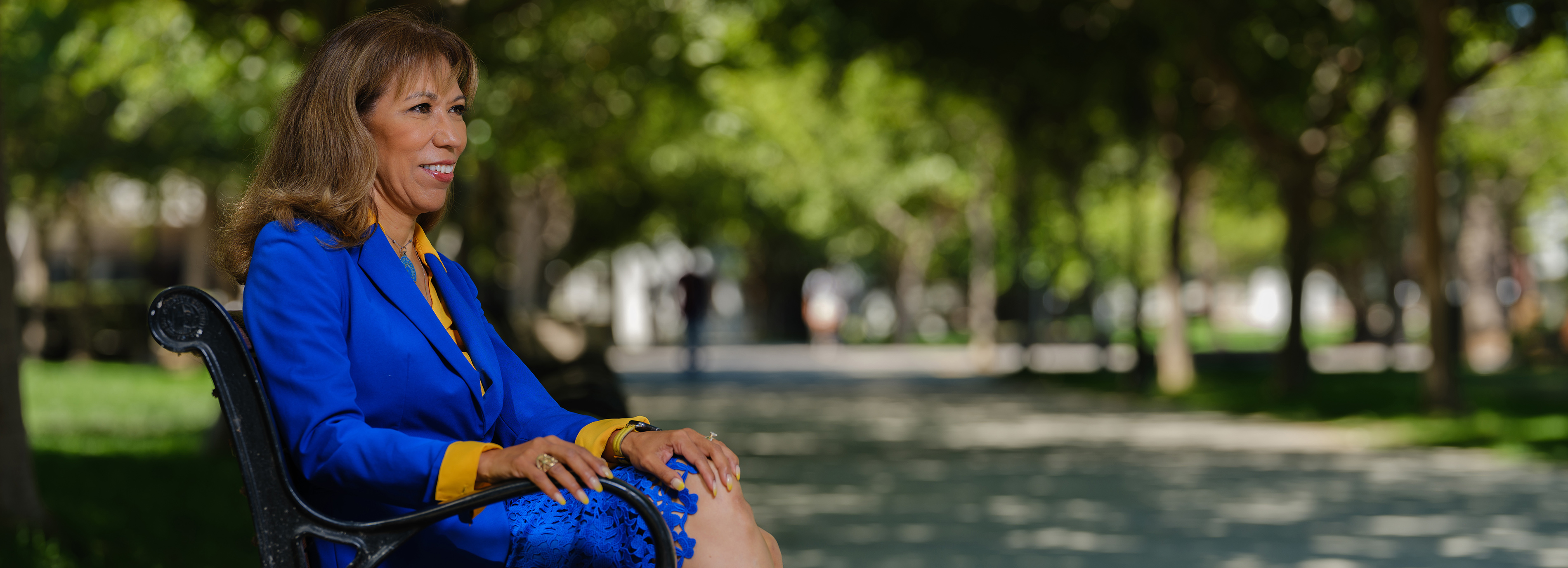 SJSU President Teniente-Matson, sitting on a bench, looking out towards SJSU.